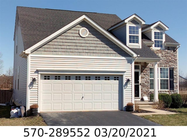392 Mogul Dr, Galloway, OH 43119 - view of front of property with driveway, stone siding, an attached garage, and a shingled roof