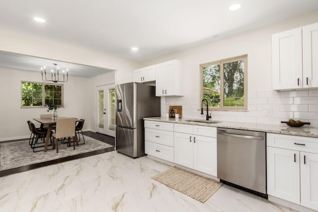 2664 Sonata Dr, Columbus, OH 43209 - kitchen with appliances with stainless steel finishes, white cabinetry, light stone countertops, backsplash, and a chandelier