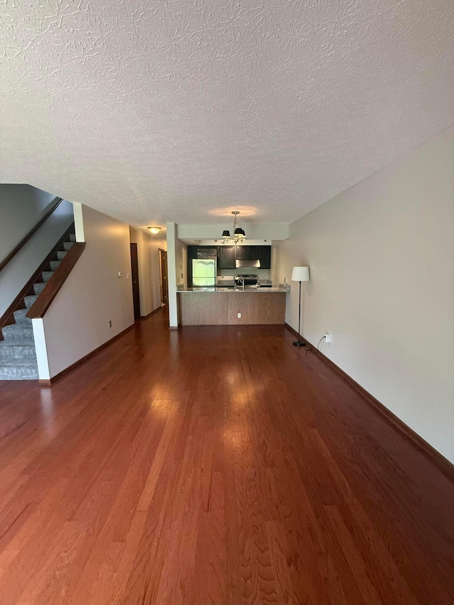 2022 Queensgate Ln, Columbus, OH 43235 - unfurnished living room featuring wood finished floors, a textured ceiling, and stairway
