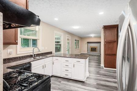 5200 Garmouth Ct, Columbus, OH 43221 - kitchen featuring freestanding refrigerator, black gas range oven, light wood finished floors, a peninsula, and exhaust hood