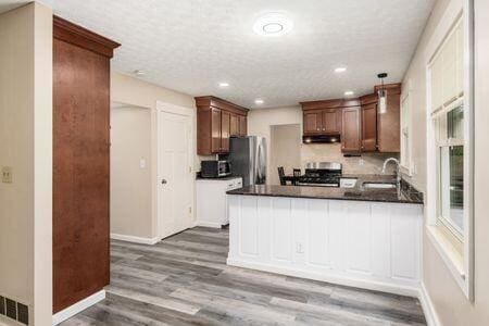 5200 Garmouth Ct, Columbus, OH 43221 - kitchen featuring freestanding refrigerator, stove, dark countertops, wood finished floors, and a peninsula