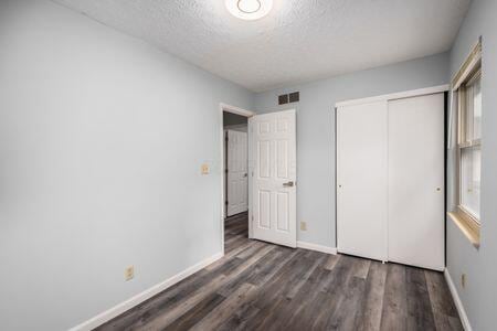 5200 Garmouth Ct, Columbus, OH 43221 - unfurnished bedroom featuring a textured ceiling, wood finished floors, and a closet