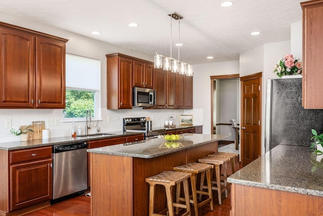 6923 Bishops Crossing Cir, Dublin, OH 43016 - kitchen with appliances with stainless steel finishes, a breakfast bar area, decorative backsplash, dark wood finished floors, and recessed lighting