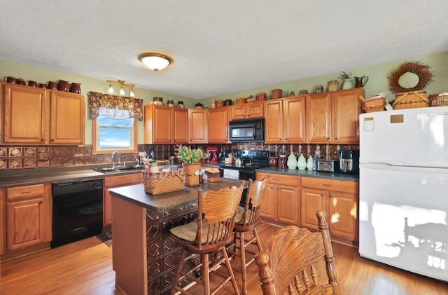 12232 Cleo Rd, Orient, OH 43146 - kitchen featuring black appliances, dark countertops, decorative backsplash, light wood-type flooring, and a textured ceiling