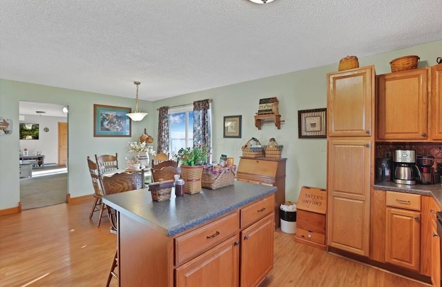 12232 Cleo Rd, Orient, OH 43146 - kitchen featuring a textured ceiling, light wood finished floors, dark countertops, a kitchen island, and brown cabinetry