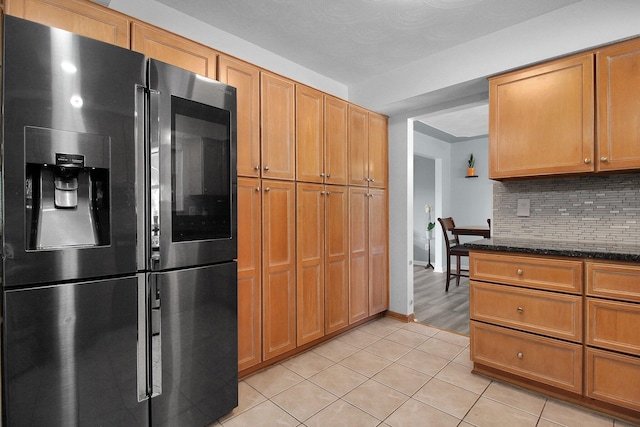 6146 Catawba Dr, Grove City, OH 43123 - kitchen with stainless steel fridge with ice dispenser, decorative backsplash, light tile patterned floors, dark stone counters, and brown cabinetry