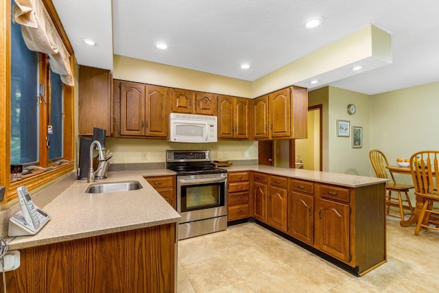 976 Hillside Dr, Newark, OH 43055 - kitchen with white microwave, stainless steel electric range, a peninsula, brown cabinets, and light tile patterned floors