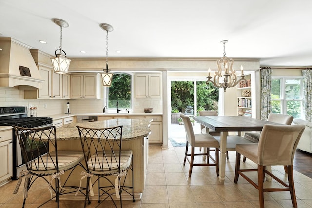 371 Ashworth Ct, Dublin, OH 43017 - kitchen with stainless steel range with gas cooktop, a chandelier, custom exhaust hood, decorative backsplash, and light tile patterned floors