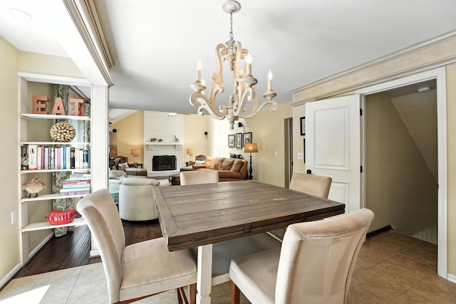 371 Ashworth Ct, Dublin, OH 43017 - tiled dining space with a chandelier, a brick fireplace, and vaulted ceiling