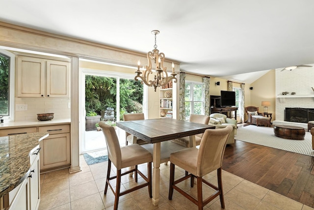 371 Ashworth Ct, Dublin, OH 43017 - dining area featuring a chandelier, light tile patterned flooring, a fireplace, and lofted ceiling