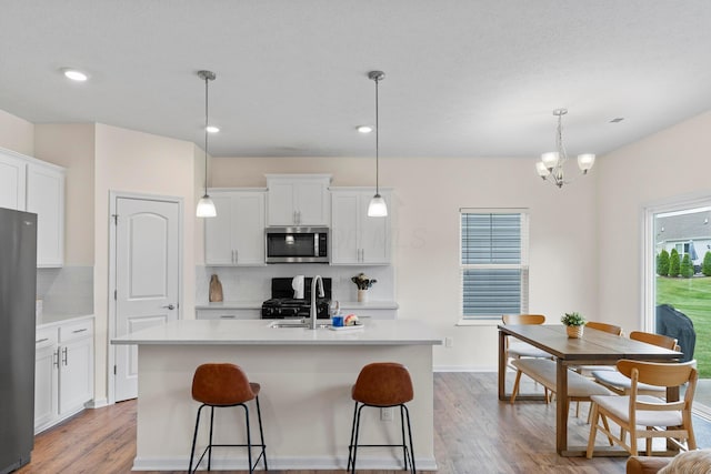 507 Curry Dr, Pataskala, OH 43062 - kitchen featuring stainless steel appliances, decorative backsplash, light wood-type flooring, an island with sink, and light countertops
