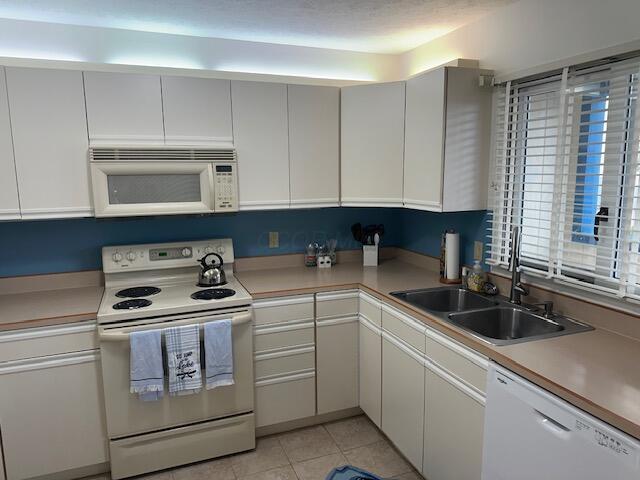 241 Chase Ave Unit B1L, Russells Point, OH 43348 - kitchen featuring white appliances, light countertops, light tile patterned flooring, and white cabinetry