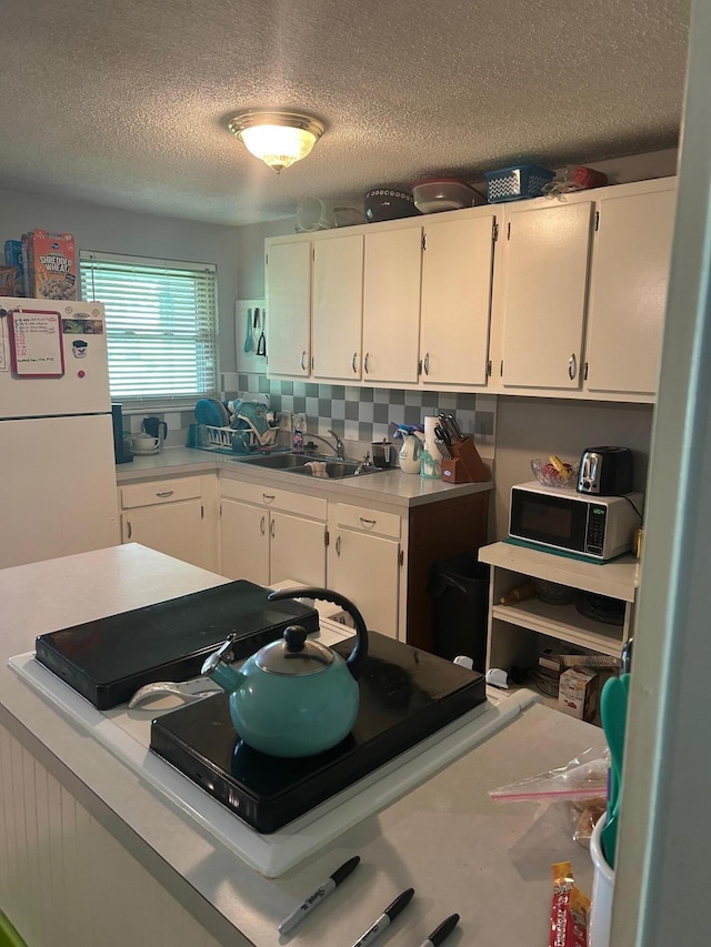 6942 Bartlett Rd, Reynoldsburg, OH 43068 - kitchen featuring freestanding refrigerator, black microwave, white cabinetry, light countertops, and a textured ceiling