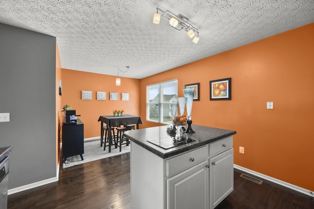 5466 Bull Creek Dr Unit 101, Dublin, OH 43016 - kitchen featuring dark wood-type flooring, dark countertops, a kitchen island, white cabinets, and pendant lighting