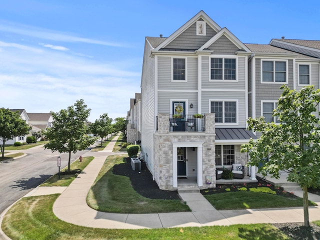 5466 Bull Creek Dr Unit 101, Dublin, OH 43016 - view of front of house with stone siding, a balcony, and a standing seam roof