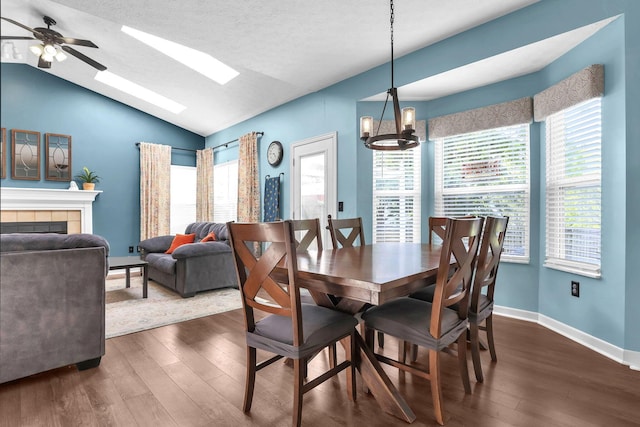 8512 Squad Dr, Galloway, OH 43119 - dining area with dark wood-style flooring, a skylight, vaulted ceiling, a fireplace, and a ceiling fan