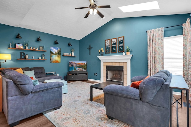 8512 Squad Dr, Galloway, OH 43119 - living area featuring wood finished floors, ceiling fan, vaulted ceiling, a skylight, and a tiled fireplace