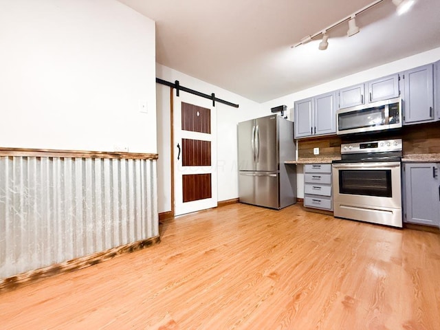 206 William St, Fulton, OH 43321 - kitchen with stainless steel appliances, gray cabinets, track lighting, a barn door, and light wood-type flooring