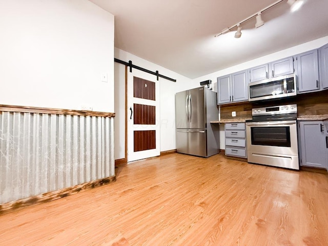 206 William St, Fulton, OH 43321 - kitchen with appliances with stainless steel finishes, gray cabinets, a barn door, rail lighting, and light wood-type flooring
