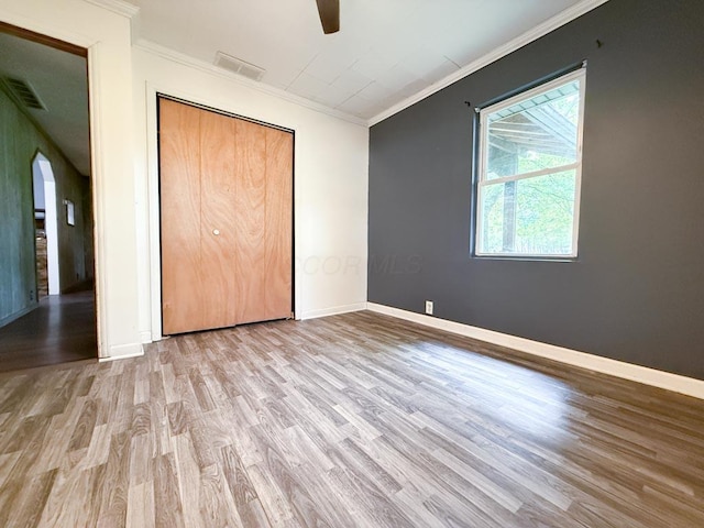 206 William St, Fulton, OH 43321 - unfurnished bedroom featuring wood finished floors, arched walkways, ornamental molding, a ceiling fan, and a closet