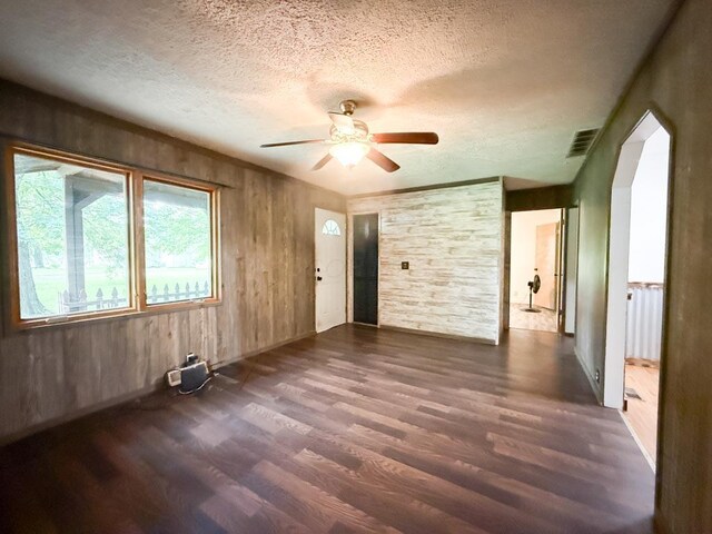 206 William St, Fulton, OH 43321 - empty room featuring dark wood-type flooring, a textured ceiling, ceiling fan, and wood walls
