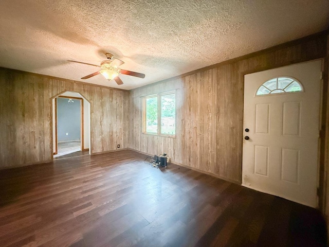 206 William St, Fulton, OH 43321 - foyer with a textured ceiling, arched walkways, ceiling fan, dark wood-style floors, and wooden walls