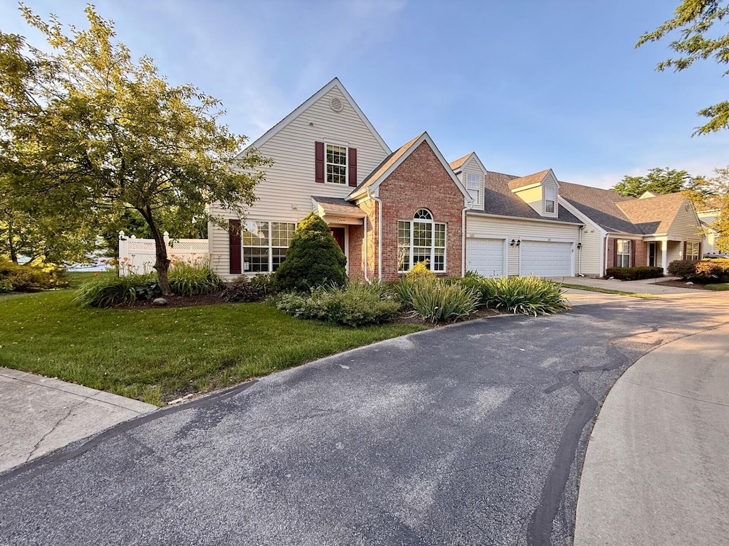 8699 Lazelle Commons Dr, Lewis Center, OH 43035 - view of front facade featuring driveway, brick siding, a front yard, and a garage