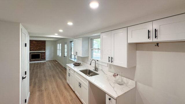 5078 Grassland Dr, Dublin, OH 43016 - kitchen with recessed lighting, light wood-type flooring, white cabinets, a brick fireplace, and open floor plan