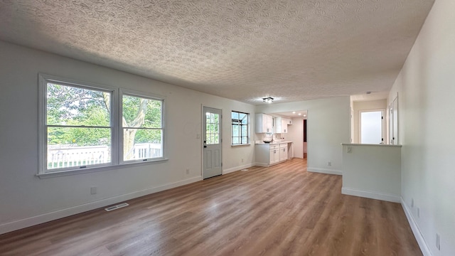 5078 Grassland Dr, Dublin, OH 43016 - unfurnished living room with light wood-type flooring and a textured ceiling