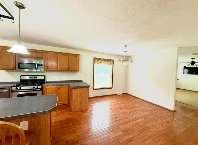 13944 Lafayette Rd, Utica, OH 43080 - kitchen featuring appliances with stainless steel finishes, dark countertops, brown cabinetry, a chandelier, and hardwood / wood-style flooring