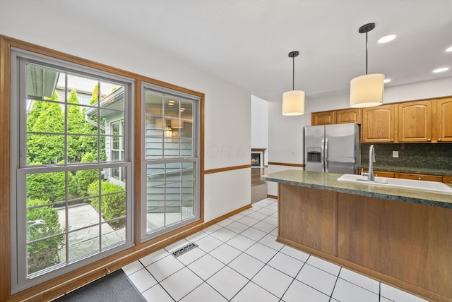 1280 Gemstone Sq W, Westerville, OH 43081 - kitchen featuring stainless steel refrigerator with ice dispenser, decorative light fixtures, backsplash, light tile patterned flooring, and a lit fireplace