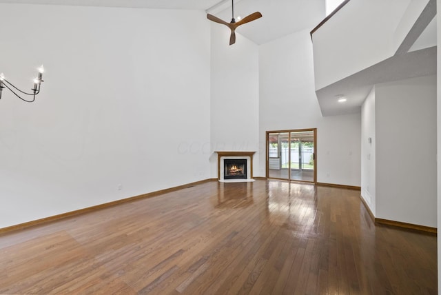 1280 Gemstone Sq W, Westerville, OH 43081 - unfurnished living room with high vaulted ceiling, hardwood / wood-style floors, a fireplace with flush hearth, a chandelier, and a ceiling fan