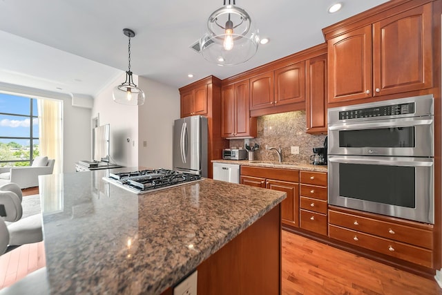 1475 W 3rd Ave Unit 401, Columbus, OH 43212 - kitchen with appliances with stainless steel finishes, dark stone counters, tasteful backsplash, pendant lighting, and light wood-type flooring
