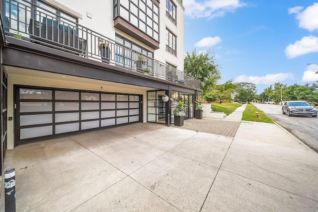 1475 W 3rd Ave Unit 401, Columbus, OH 43212 - view of home's exterior featuring a balcony, a garage, stucco siding, and driveway