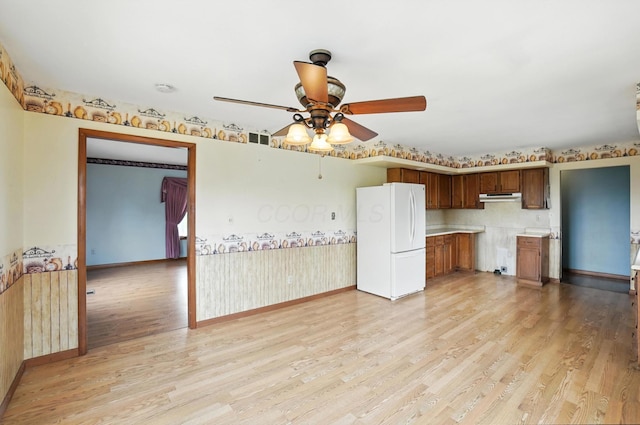 24 W High St, Jeffersonville, OH 43128 - kitchen with freestanding refrigerator, light wood-style flooring, a ceiling fan, light countertops, and brown cabinetry