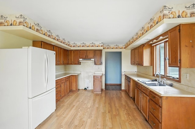 24 W High St, Jeffersonville, OH 43128 - kitchen with freestanding refrigerator, light wood-type flooring, brown cabinetry, and light countertops