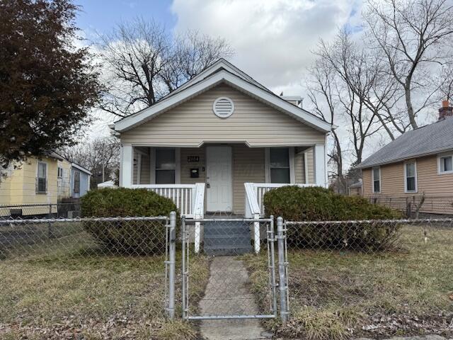 shotgun-style home with covered porch, a gate, and a fenced front yard