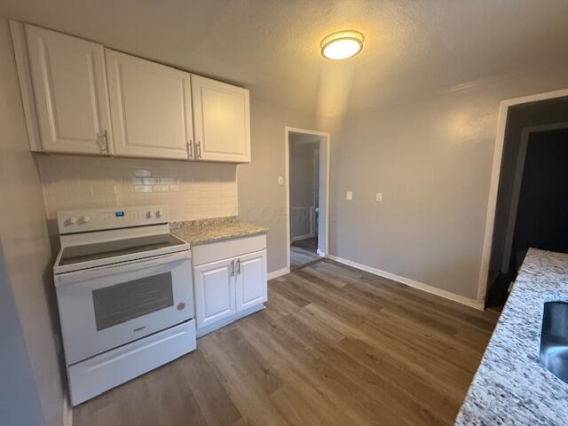 kitchen with white range with electric stovetop, wood finished floors, and white cabinets
