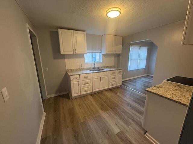 kitchen with white cabinetry, wood finished floors, and a textured ceiling