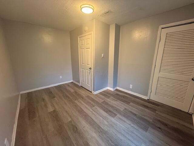 unfurnished bedroom with wood finished floors, a closet, and a textured ceiling