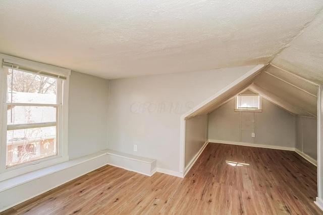 bonus room with a textured ceiling, wood finished floors, and lofted ceiling