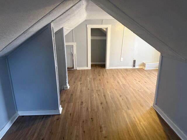 bonus room featuring vaulted ceiling, wood finished floors, and a textured ceiling