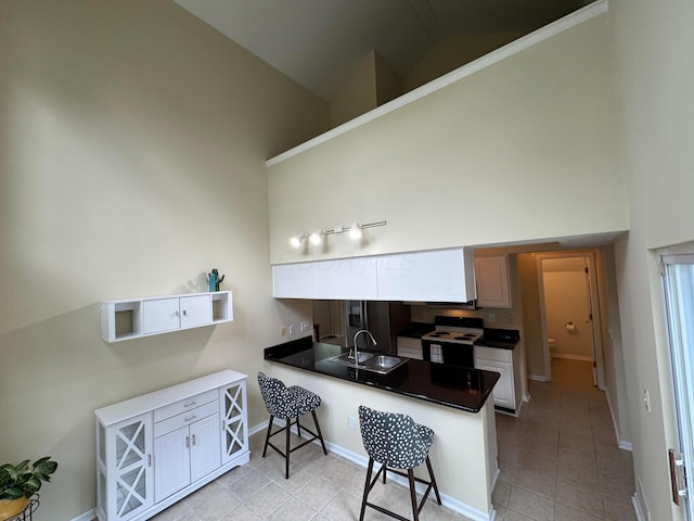 6282 Mcnaughten Place Ln Unit 39, Columbus, OH 43213 - kitchen featuring high vaulted ceiling, a peninsula, a kitchen breakfast bar, light tile patterned flooring, and white electric range