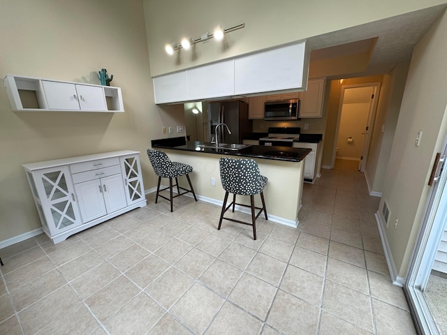 6282 Mcnaughten Place Ln Unit 39, Columbus, OH 43213 - kitchen with a peninsula, light tile patterned floors, a kitchen bar, stainless steel microwave, and electric range