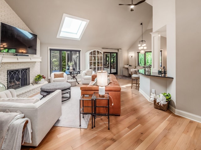 5767 Loch Maree Ct, Dublin, OH 43017 - living room featuring a skylight, high vaulted ceiling, light wood-style floors, a fireplace, and healthy amount of natural light