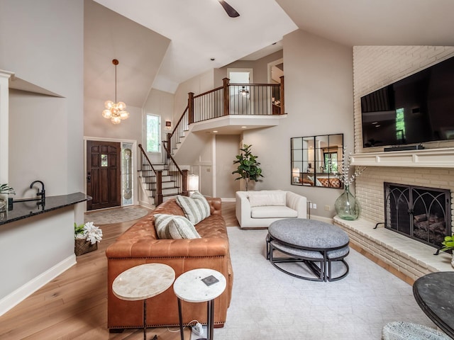 5767 Loch Maree Ct, Dublin, OH 43017 - living room with high vaulted ceiling, wood finished floors, stairway, a chandelier, and a fireplace
