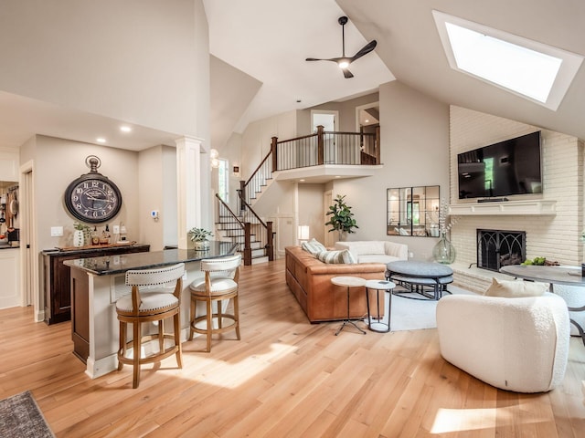 5767 Loch Maree Ct, Dublin, OH 43017 - living room featuring high vaulted ceiling, light wood-type flooring, stairs, a fireplace, and a skylight