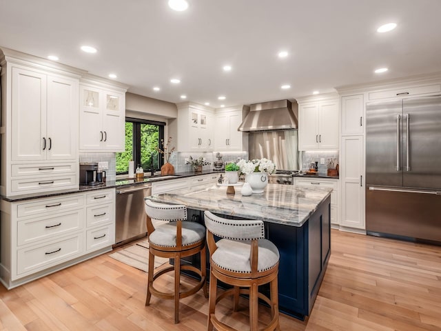 5767 Loch Maree Ct, Dublin, OH 43017 - kitchen with appliances with stainless steel finishes, wall chimney exhaust hood, light wood-style floors, tasteful backsplash, and recessed lighting
