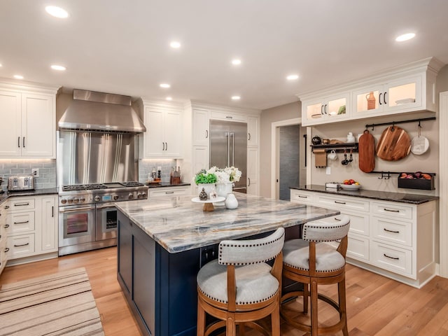 5767 Loch Maree Ct, Dublin, OH 43017 - kitchen with premium appliances, wall chimney exhaust hood, white cabinetry, decorative backsplash, and recessed lighting