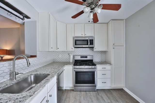 7617 Whitneyway Dr Unit 120, Columbus, OH 43085 - kitchen with appliances with stainless steel finishes, a ceiling fan, white cabinets, backsplash, and light stone countertops